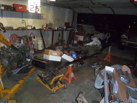 1968 Ford Bronco - Garage scene with engine hoist and various vehicle parts laid out for work.