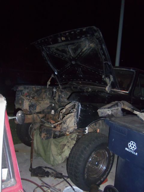 1968 Ford Bronco - The front end of a vehicle is shown with the hood open and the engine compartment largely disassembled.