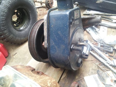1986 Ford Bronco - A blue power steering pump with a pulley is shown, alongside other vehicle parts like a tire and axle.