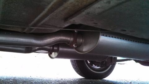 1966 Ford Falcon - The underside of a vehicle shows its exhaust pipes and mufflers, with a tire visible on the right.
