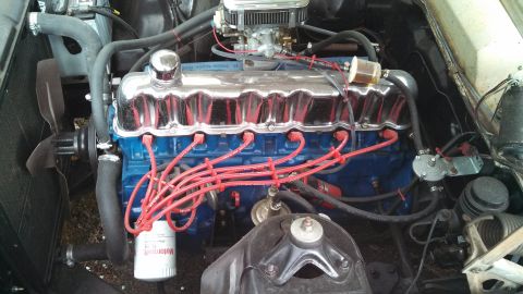 1966 Ford Falcon - The engine bay of a 1966 Ford Falcon features a blue engine block, chrome valve covers, and red spark plug wires, indicating a V8 engine.