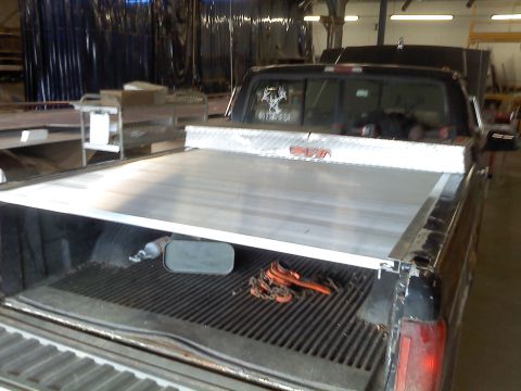 1995 Ford F-150 - The rear of a 1995 Ford F-150 pickup truck is shown with a diamond plate toolbox and a tonneau cover over the bed.