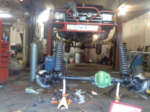 1995 Ford F-150 - Front axle and suspension parts for a Ford truck are laid out for work in a garage.