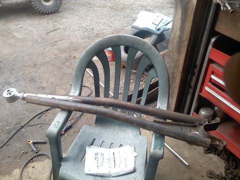 1995 Ford F-150 - Rusty suspension control arms sit on a chair in a workshop setting.