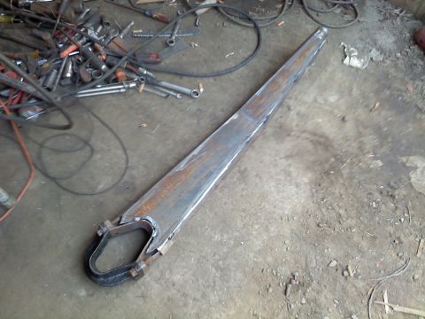 1995 Ford F-150 - A custom-fabricated suspension component rests on the floor of a workshop, surrounded by tools and equipment.