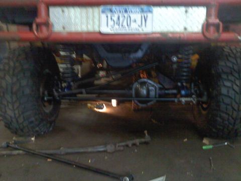 1995 Ford F-150 - The underside of a heavily modified truck, showing its rear axle, suspension, and large off-road tires.