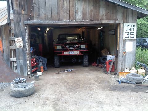 1995 Ford F-150 - A heavily modified pickup truck sits inside a rustic garage, a prominent red bull bar and off-road tires.