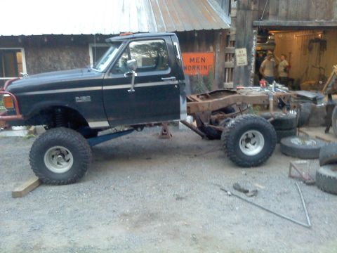1995 Ford F-150 - This modified Ford F-150 truck has had its rear section removed and is supported by jacks and large off-road tires.