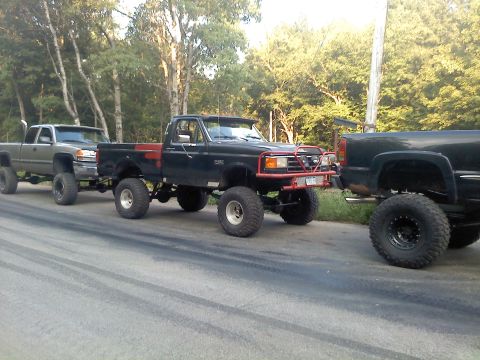 1995 Ford F-150 - Three heavily modified pickup trucks are lined up on a paved road.