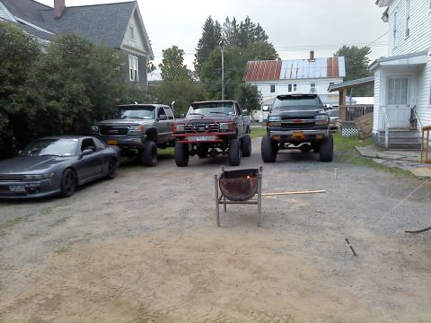 1995 Ford F-150 - A collection of modified vehicles, including trucks and a sports car, are parked together in an outdoor setting.