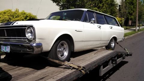1966 Ford Falcon - White 1966 Ford Falcon wagon being transported on a flatbed trailer.