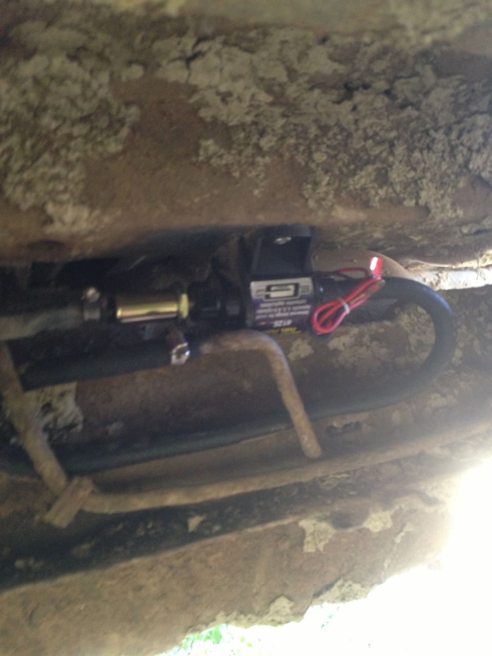 electric fuel pump with red wire and black hose attached to metal lines
