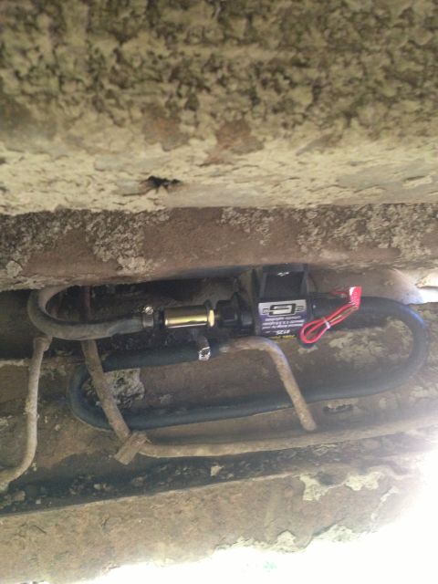 1979 Ford Bronco - An aftermarket electric fuel pump is installed on the undercarriage of a vehicle, connected to fuel lines.