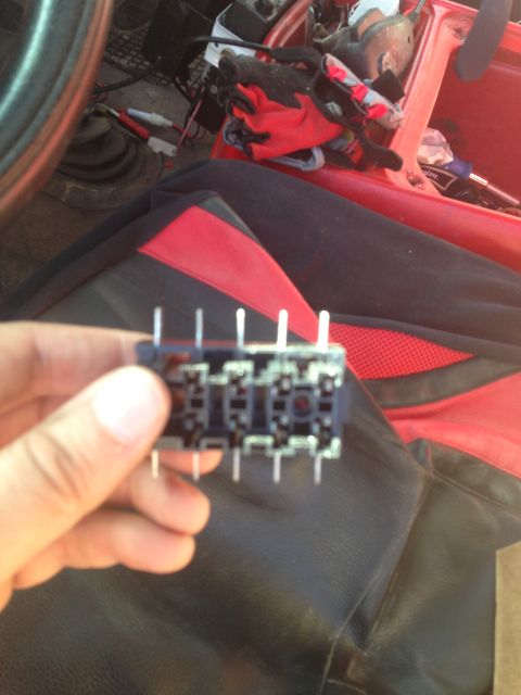 1979 Ford Bronco - A hand holds a relay socket, with the interior of a vehicle red and black seats visible in the background.