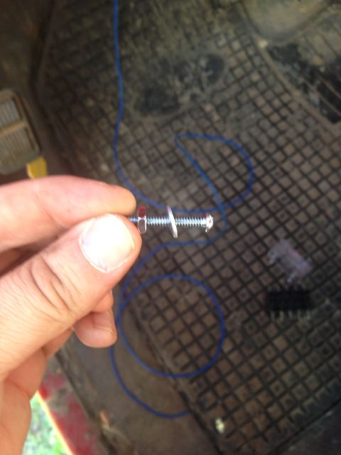 1979 Ford Bronco - Close-up of a hand holding a bolt with washers and a nut, with blue wire in the background.
