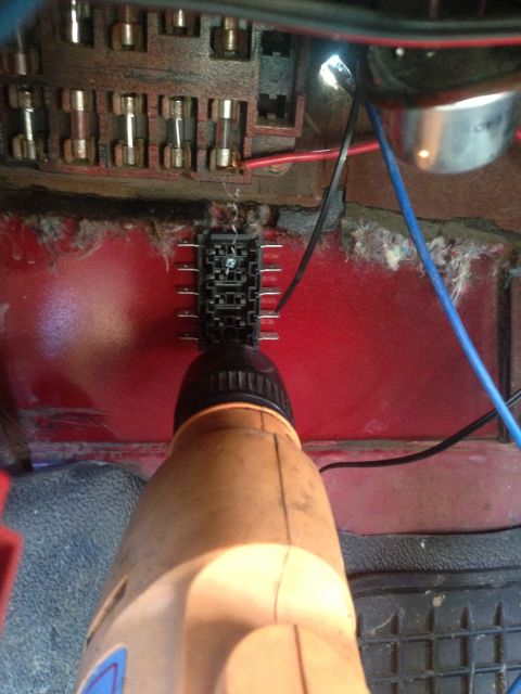 1979 Ford Bronco - A drill is positioned near a vehicle's fuse box and wiring harness.