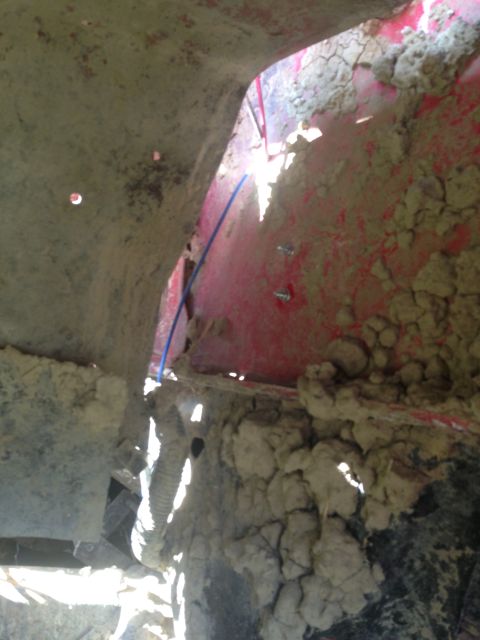 1979 Ford Bronco - The underside of a vehicle is covered in mud, with some red paint showing through.