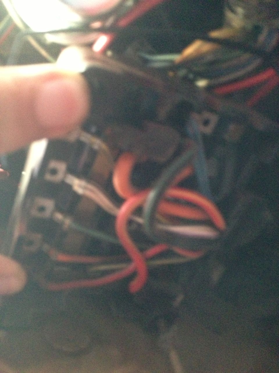 Close-up of a tangled automotive wiring harness with red, orange, and blue wires