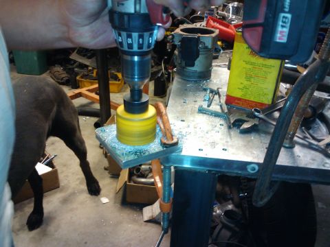 1995 Ford Probe - A person is drilling a hole in a metal plate clamped to a workbench, with a dog in the background.