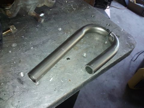 1995 Ford Probe - A bent metal tube part sits on a workbench, with a Supermotors.net watermark visible.