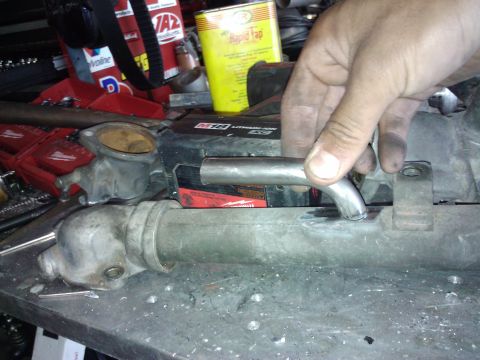 1995 Ford Probe - Automotive part on a workbench, possibly a thermostat housing and pipe.