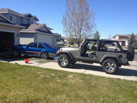 1990 Ford Mustang - A blue 1990 Ford Mustang is parked next to a grey Jeep Wrangler in a driveway.