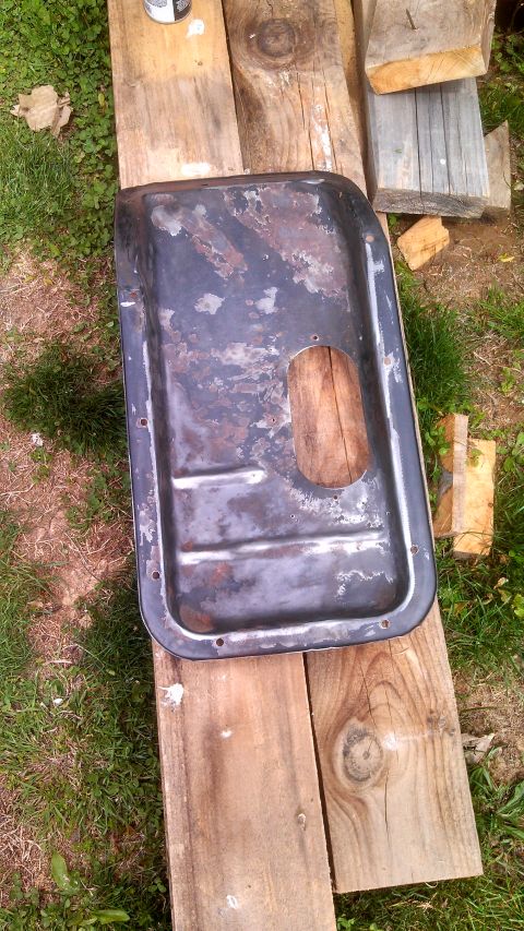 1979 Ford Bronco - A rusty oil pan rests on weathered wood planks, with grass and more wood in the background.