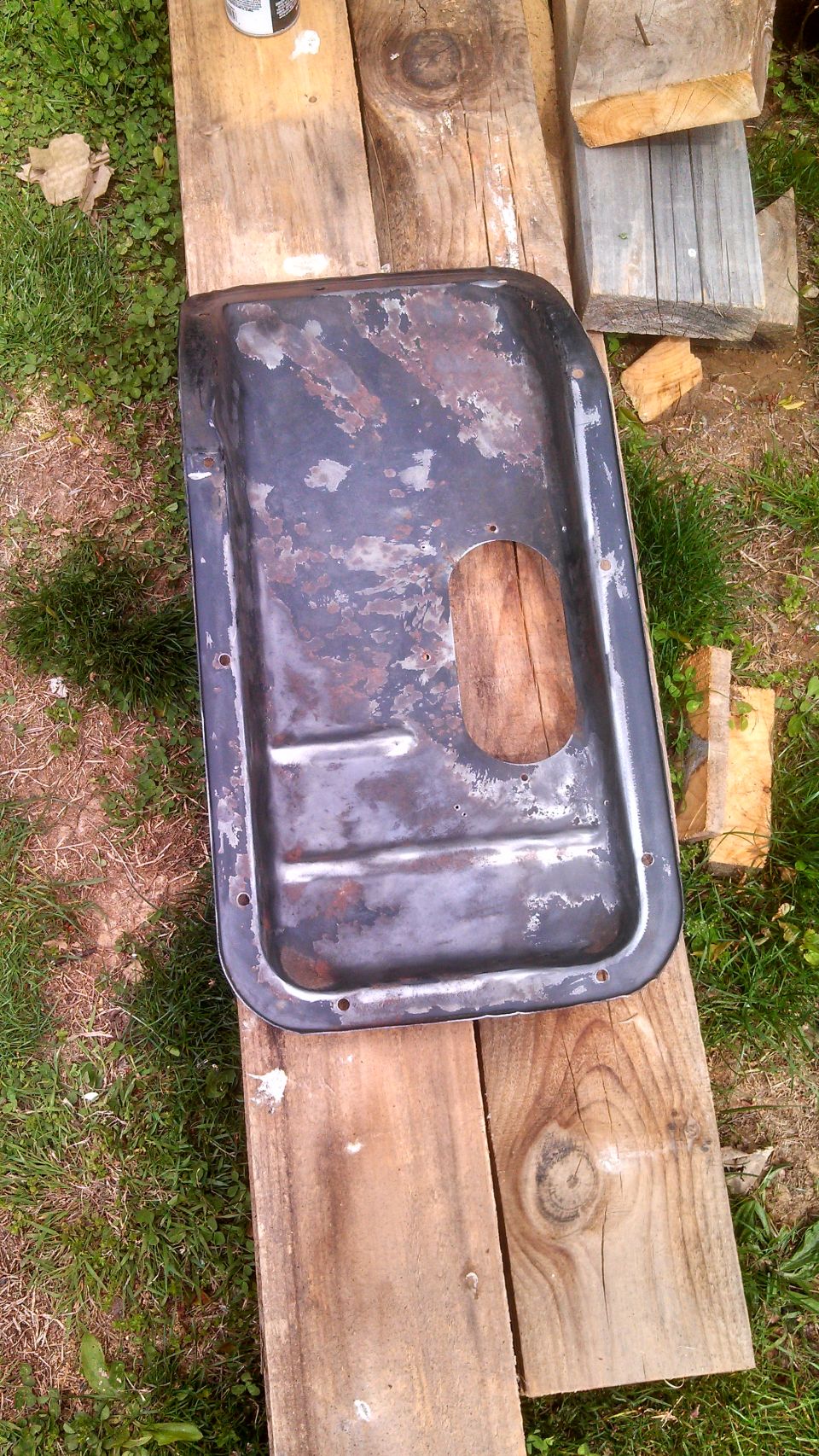 old oil pan sitting on wooden planks outside