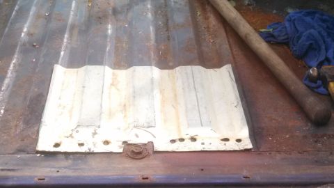 1979 Ford Bronco - A close-up view of a corrugated metal panel secured with a bolt on the surface of a truck bed.