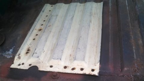 1979 Ford Bronco - A corrugated metal panel with numerous holes along its edges is shown, likely a part from a vehicle.