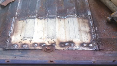 1979 Ford Bronco - A metal patch has been welded onto a corrugated surface, showing signs of repair.