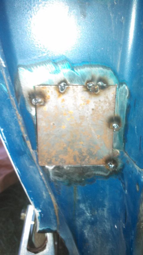 1979 Ford Bronco - A close-up view of a rusted metal patch that has been welded onto a blue vehicle's body, indicating repair work.