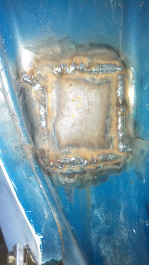 1979 Ford Bronco - A metal patch has been welded onto a blue surface, showing signs of repair work.