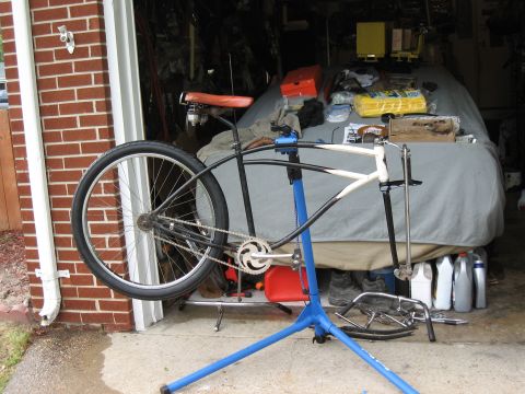 1994 Ford Bronco - A bicycle frame is mounted on a repair stand in a garage, with a car cover and various items in the background.