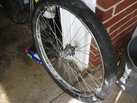 1994 Ford Bronco - A close-up of a bicycle wheel with a damaged tire, showing the spokes and hub against a brick and white door background.