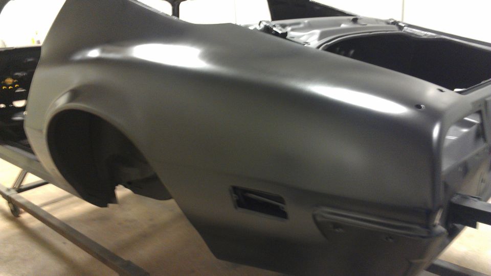 Black car body panel on a stand, showing rear quarter panel and trunk area