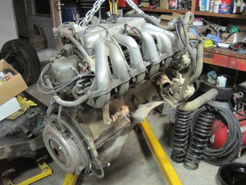 1989 Ford Bronco - Engine and transmission assembly, likely from a truck or SUV, is suspended by chains for removal or installation.