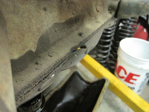 1989 Ford Bronco - Close-up view of a vehicle's undercarriage, showing a damaged frame section and suspension components.
