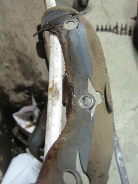 1989 Ford Bronco - Close-up of a heavily rusted metal bracket, showing signs of wear and tear, possibly from an engine compartment.