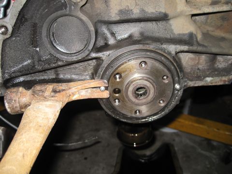 1989 Ford Bronco - Close-up view of an engine block's crankshaft seal area with a hammer tool.