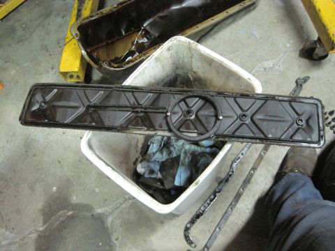 1989 Ford Bronco - Engine parts, an oil pan and valve cover, are shown in a workshop setting.