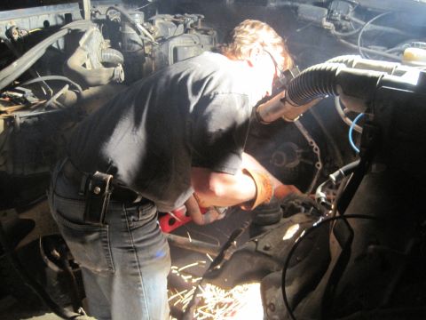 1989 Ford Bronco - Mechanic working on engine components in a vehicle's engine bay.