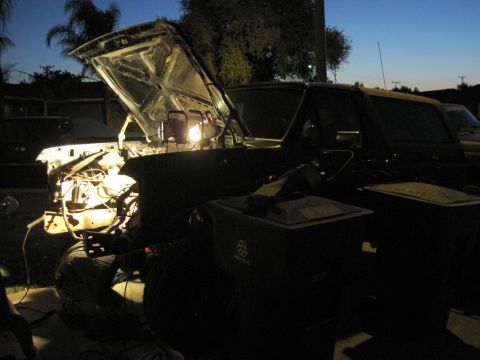 1989 Ford Bronco - The engine bay is lit up at dusk, showing some mechanical components.