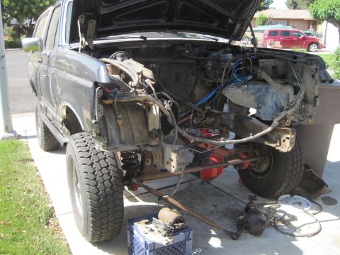 1989 Ford Bronco - The engine bay of a truck is shown with the engine removed, revealing the frame and suspension.