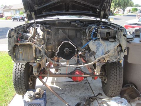 1989 Ford Bronco - The engine bay of a vehicle with the hood open, revealing the engine removed and the cross member.