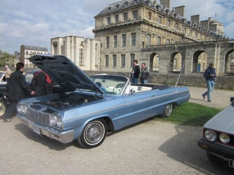 1991 Ford LTD Crown Victoria - A classic blue convertible is displayed with its hood up, in front of an old stone building.