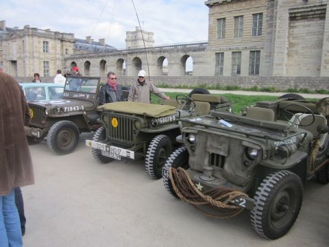 1991 Ford LTD Crown Victoria - Several vintage military jeeps are lined up outdoors in front of a large, historic building.