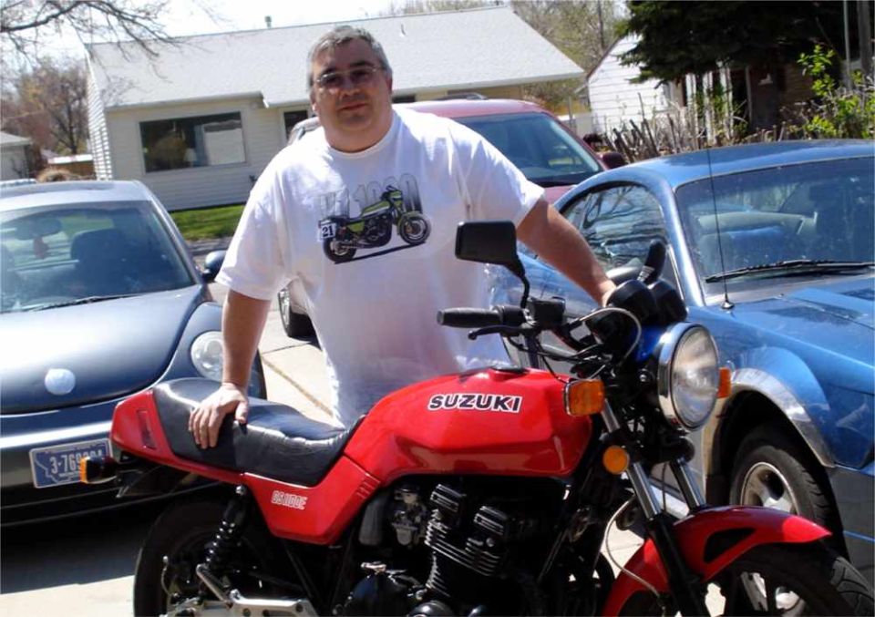 Red Suzuki motorcycle with man and blue car