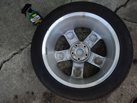 2004 Mercury Grand Marquis - A single wheel and tire assembly rests on a cracked concrete surface, with a cleaning product nearby.