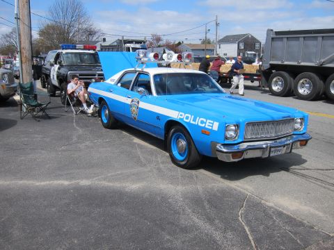 1991 Ford Crown Victoria - A classic police cruiser is parked on the street, with a dump truck and other vehicles in the background.